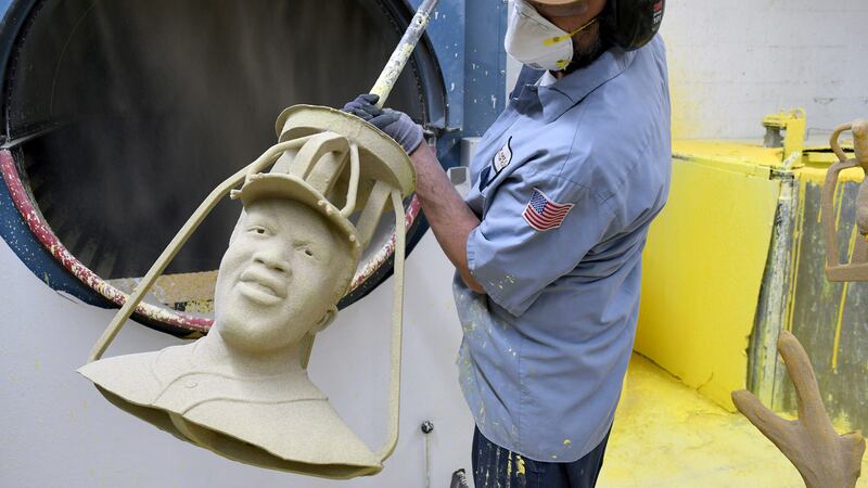 Jesse Justus, an employee at Art Castings of Colorado, touches up a wax mold of Jackie...