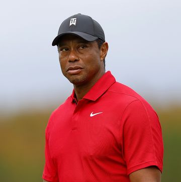tiger woods wearing a red nike shirt and looking out toward a golf course