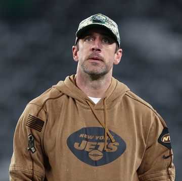 aaron rodgers wearing a camouflage hat and looking upward