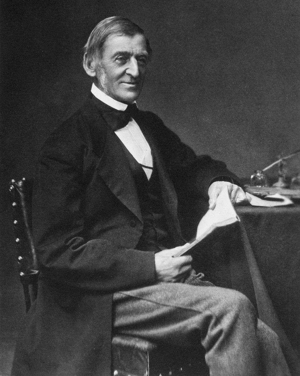 ralph waldo emerson sitting at a table and holding a book as he looks up