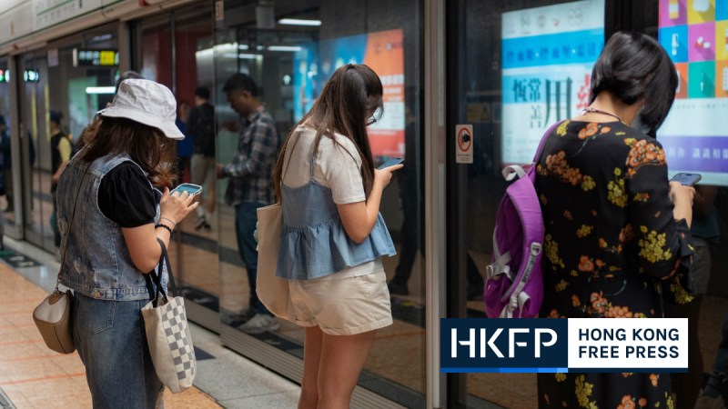 Residents using their phones at MTR stations in Hong Kong. File photo: Kyle Lam/HKFP.
