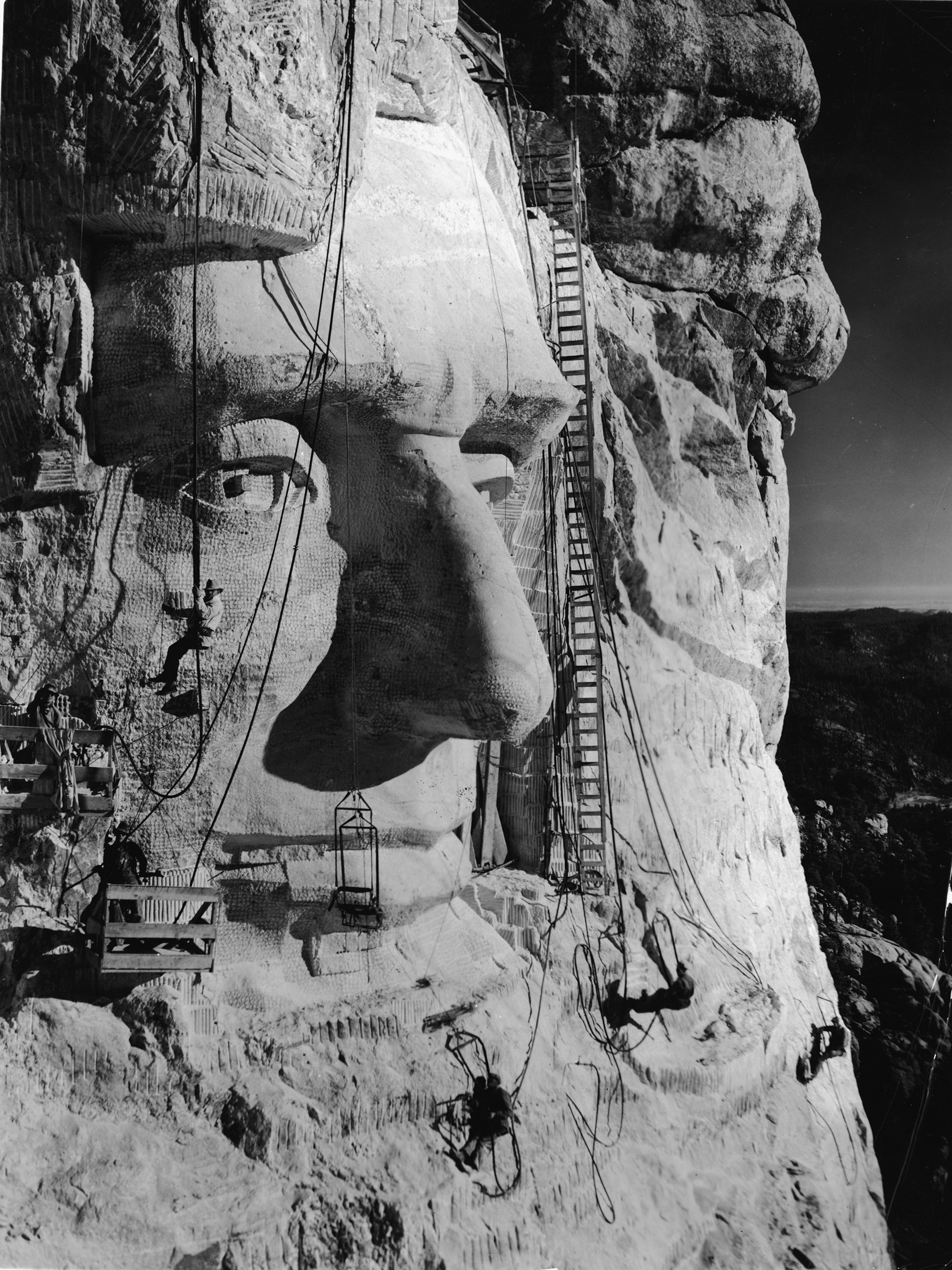 A sculptor hanging from the carving of the head of Abraham Lincoln on Mount Rushmore