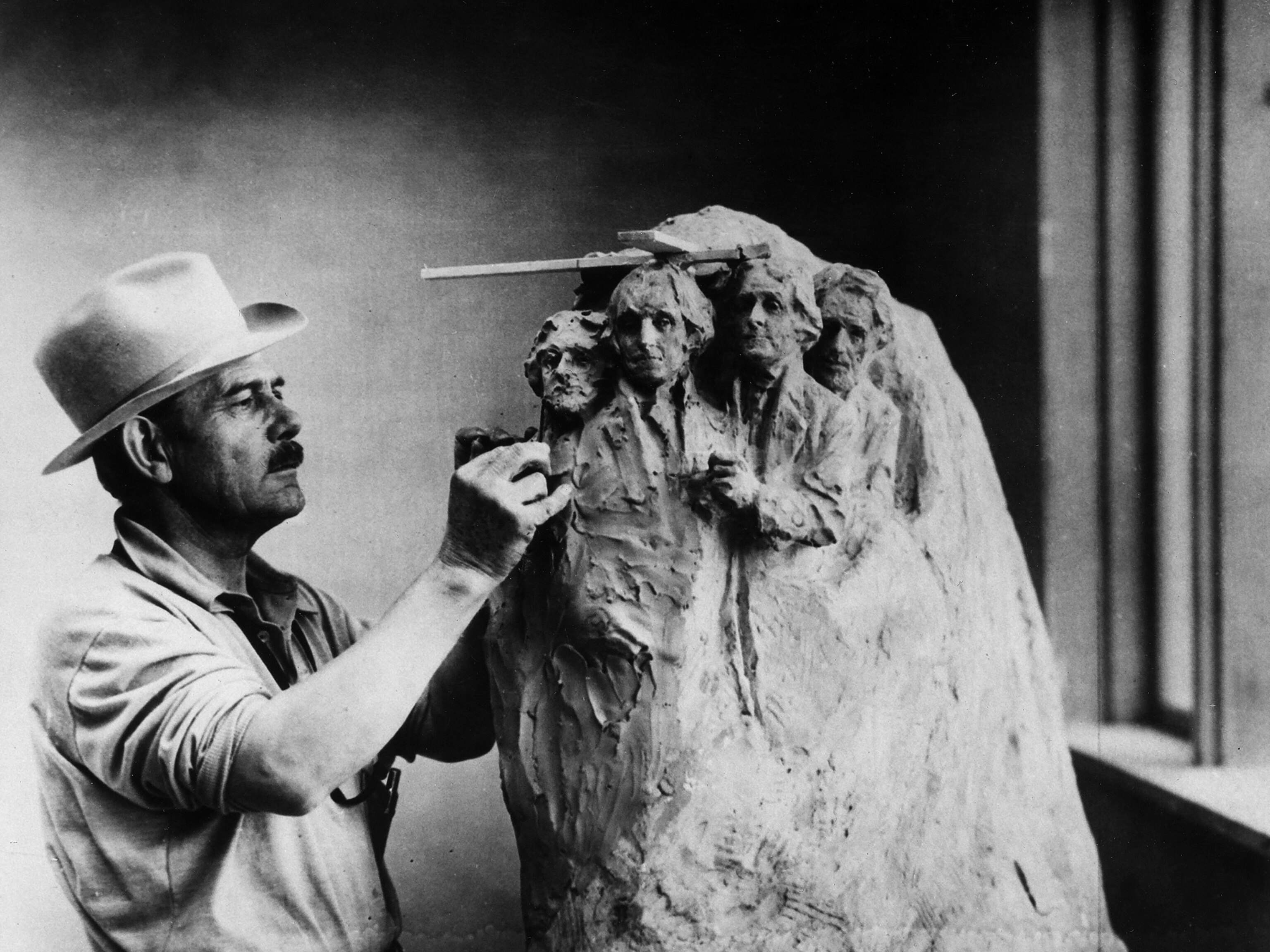 a sculptor working on a smaller draft for Mount Rushmore