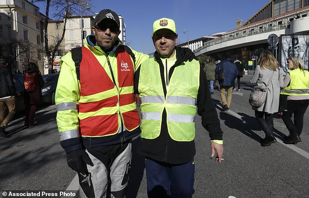 Unionist from the CGT (General Working Confederation) Mourad, left, and Yellow Vest protester Daniel pose together during a march in Marseille, southern France, Tuesday, Feb. 5, 2019. French public workers are striking in protest against French President Emmanuel Macron's policies and demonstrations are taking place across the country with the CGT labor union calling for a general strike. (AP Photo/Claude Paris)