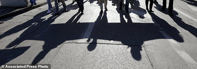 Unionists from the CGT (General Working Confederation) cast their shadow during a march in Marseille, southern France, Tuesday, Feb. 5, 2019. French public workers are striking in protest against French President Emmanuel Macron's policies and demonstrations are taking place across the country with the CGT labor union calling for a general strike. (AP Photo/Claude Paris)