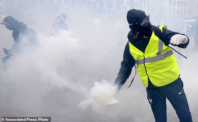 A demonstrator returns a tear gas grenade during a demonstration called by the CGT (General Working Confederation) union, Tuesday, Feb. 5, 2019 in Lille, northern France. Workers, public servants, and retired people were invited to march during a strike called by the CGT (General Working Confederation) union. (AP Photo/Michel Spingler)