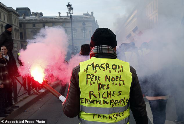 A demonstrator wearing a yellow vests reading "Macron, Santa Claus for the rich, ennemy of the French people" takes part to a demonstration called by the CGT (General Working Confederation) union, Tuesday, Feb. 5, 2019 in Paris. Workers, public servants, and retired people were invited to march during a strike called by the CGT (General Working Confederation) union. (AP Photo/Michel Euler)