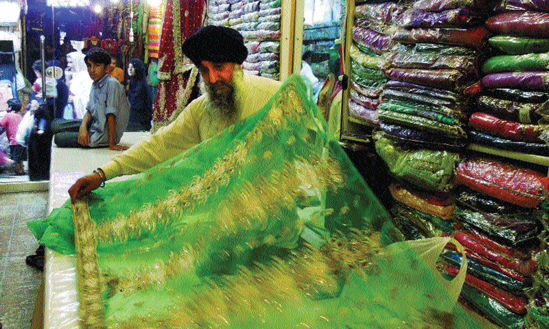 Saroop Singh display a dress at his shop in Moti Bazaar.