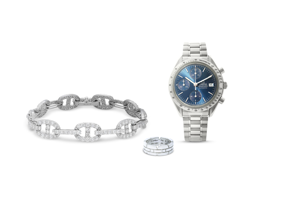 A Rachel Koen Round Cut Diamond Link bracelet, a Cartier Tank Francaise ring, and an OMEGA Speedmaster Chronograph Steel Blue Dial Automatic men's watch against a light blue background.