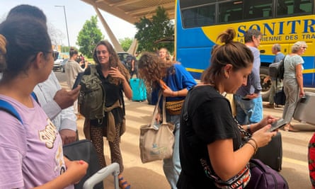 French nationals gather as they wait to be airlifted back to France on a French military aircraft at the international airport in Niamey, Niger
