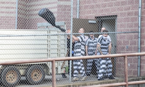 A group of prisoners seen through a chainlink fence.