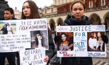 People strand holding handwritten signs with pictures of Saltanat Nukenova and writing in Kazakh and English saying 'Justice for Salta'