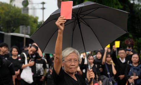 Maria Catarina Sumarsih holding up a red notebook or piece of paper.