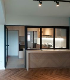 an empty kitchen and living room with wood flooring on the side, open sliding glass doors to another room