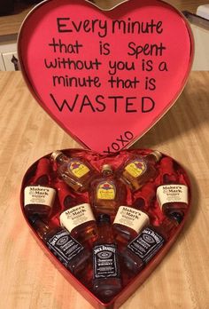 a heart shaped box filled with miniature liquor bottles and a message written on the inside