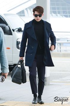a man in black coat and sunglasses carrying a bag