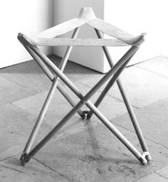 a black and white photo of a folding chair on the floor in front of a wall