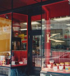 a store front with red and yellow awnings on the windows that have food in them