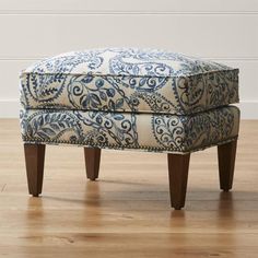 a blue and white ottoman sitting on top of a hard wood floor next to a wall