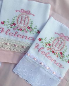 three personalized embroidered napkins on pink and white linen with lace trimming around the edges