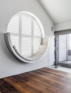a circular mirror on the wall in a room with wood flooring and white walls