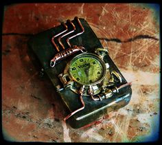 an old watch sitting on top of a piece of metal