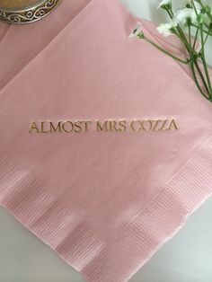two pink napkins with the words almost mrs cozzia on them next to flowers