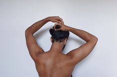 a man with no shirt on is holding his hands up to his head while standing in front of a white wall