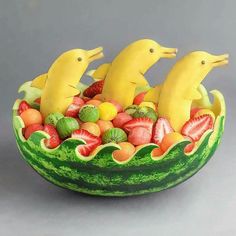 a fruit bowl with bananas, strawberries, and other fruits in it that look like dolphins