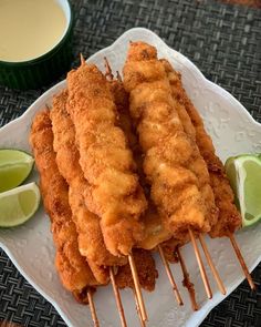 there are some fried food on a plate with toothpicks and lime wedges