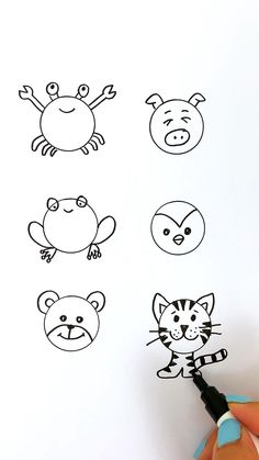 someone is drawing different animal faces on the white paper with marker and pen in their hand