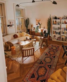 a living room filled with furniture and lots of plants on top of a hard wood floor