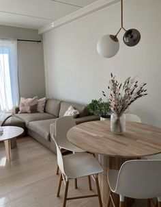 a living room filled with furniture and a wooden table surrounded by white chairs next to a window