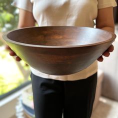 a person holding a large wooden bowl in their right hand and the other hand is holding it
