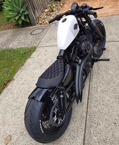 a black and white motorcycle parked on the sidewalk