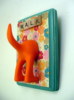 an orange elephant figurine sitting on top of a flowered wall mounted plaque