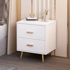 a white night stand with two gold handles on it in a bedroom next to a bed
