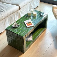 a green tiled coffee table with two candles on it
