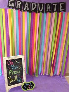 a graduation party with colorful streamers and a chalkboard sign on the table next to it