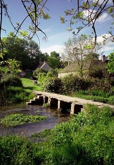a stone bridge over a small stream in a lush green field