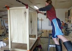 a woman working on a cabinet in a workshop