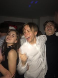 group of young people laughing and having fun at a party with one person taking a selfie