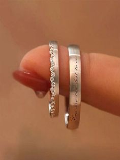 two silver rings with words on them are held in someone's hand and the other is