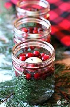 three mason jars filled with red and green christmas decorations sitting on top of a table