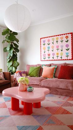 a living room filled with furniture and a pink table in front of a painting on the wall