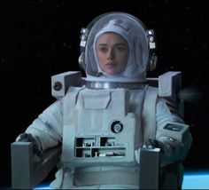 a woman in an astronaut suit standing next to a space station