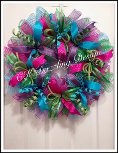 a purple and green mesh wreath hanging on a door with the words dearing design
