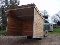 a truck is parked in front of a small wooden building with a metal roof and door