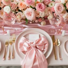 the table is set with pink and white plates, silverware, and napkins