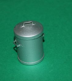 a small metal container sitting on top of a green table